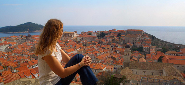Kelly sitting along the city walls looking at all the red roofs of the old town